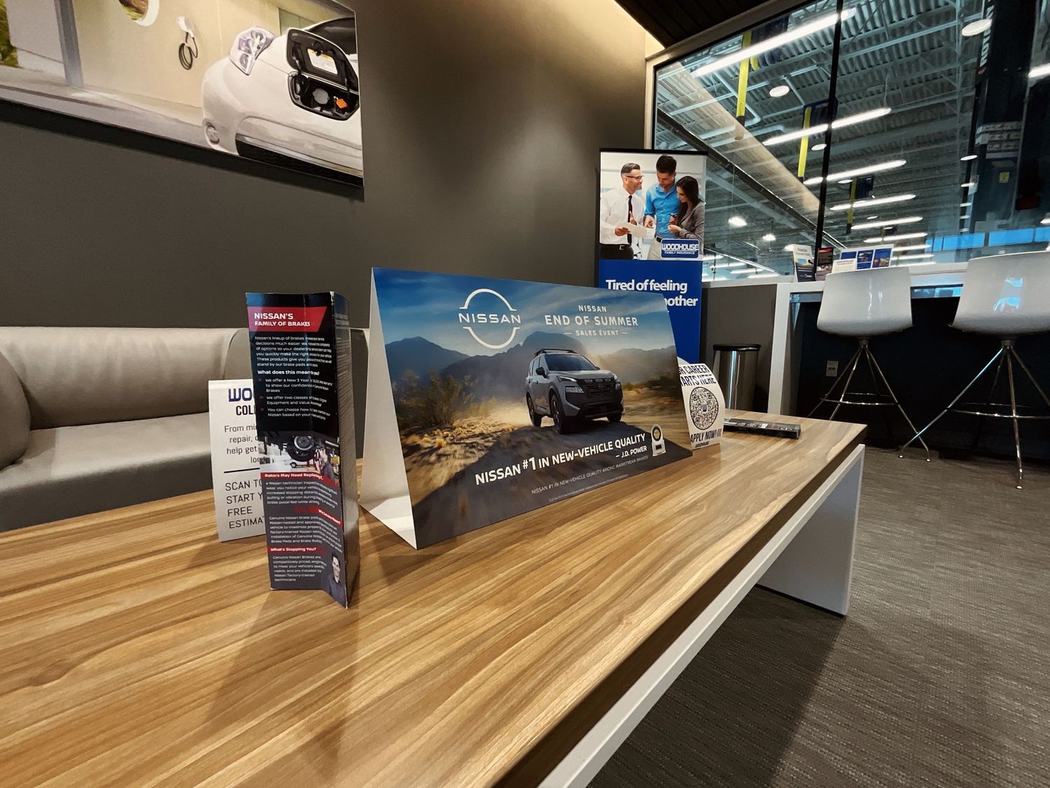Nissan vehicle display stand on a wooden counter inside a modern car dealership showroom.