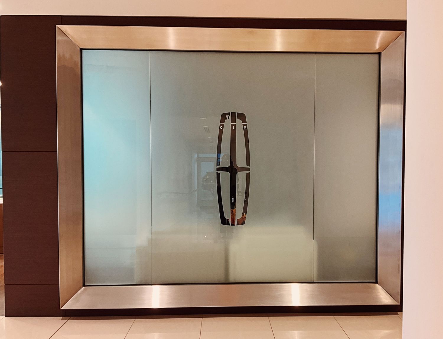 Lincoln Motor Company logo displayed on a frosted glass panel with a sleek metallic frame in a modern showroom setting.