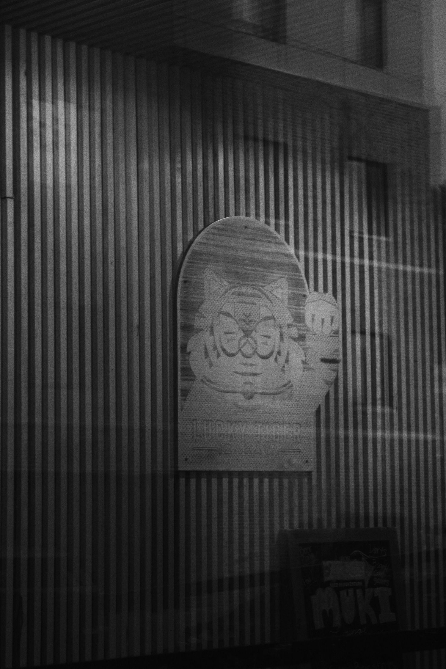 Black and white photo of a cartoon character poster on a corrugated metal wall at night.