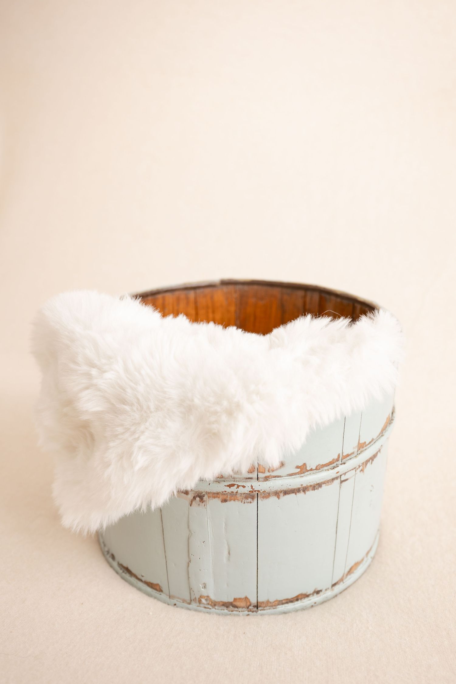 Rustic light blue wooden barrel with white faux fur draped over the edge, perfect for newborn photography prop.