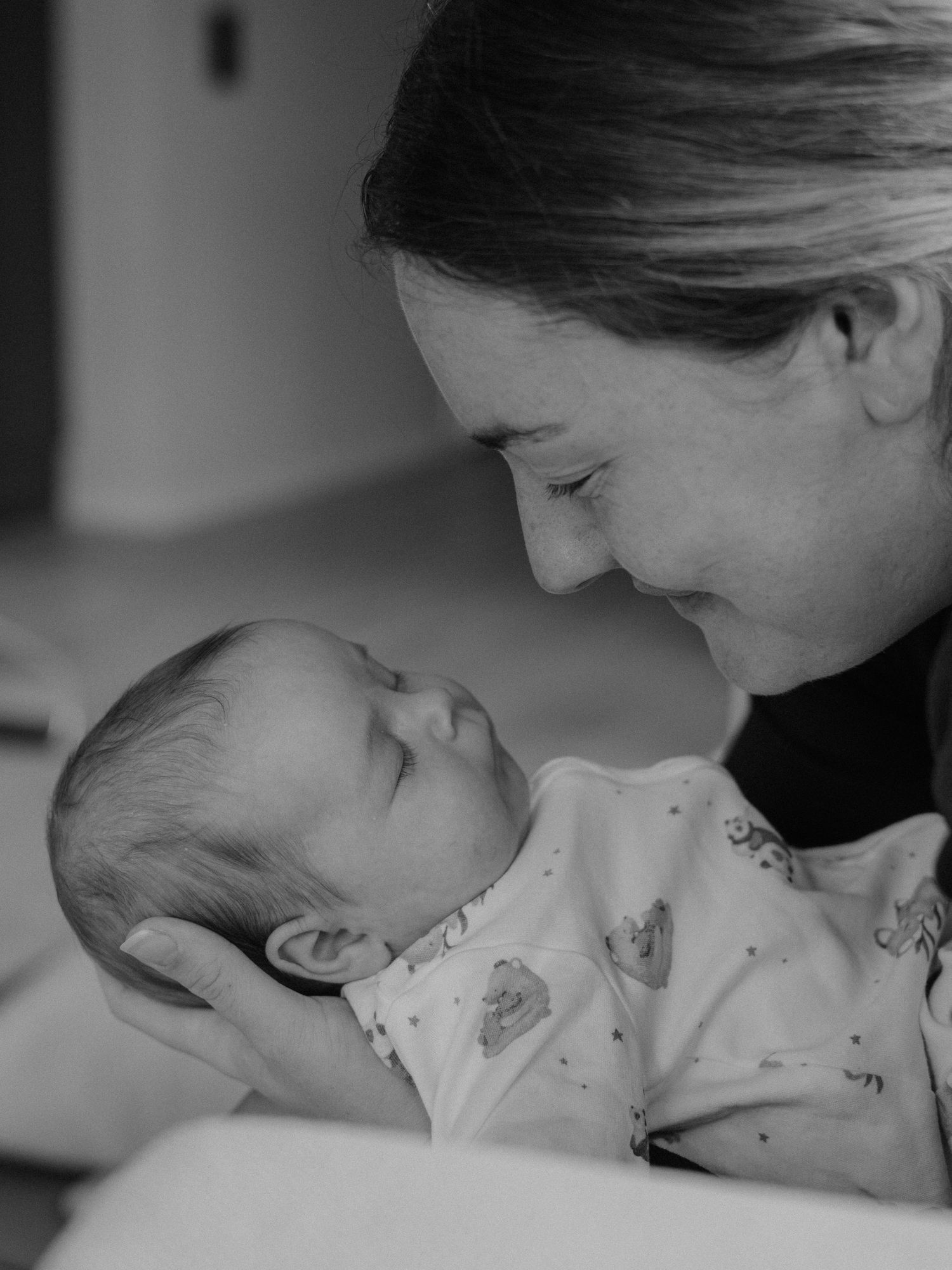 Mamma med sin nyfödda bebis under en naturlig och intim familjefotografering i Stockholm.