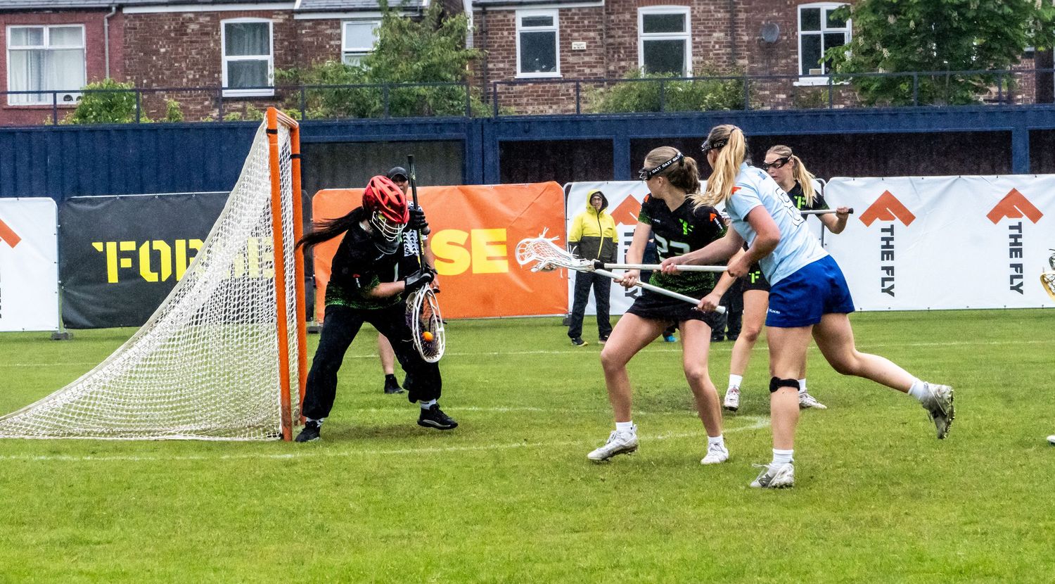Women's lacrosse players attack the goal during a match.