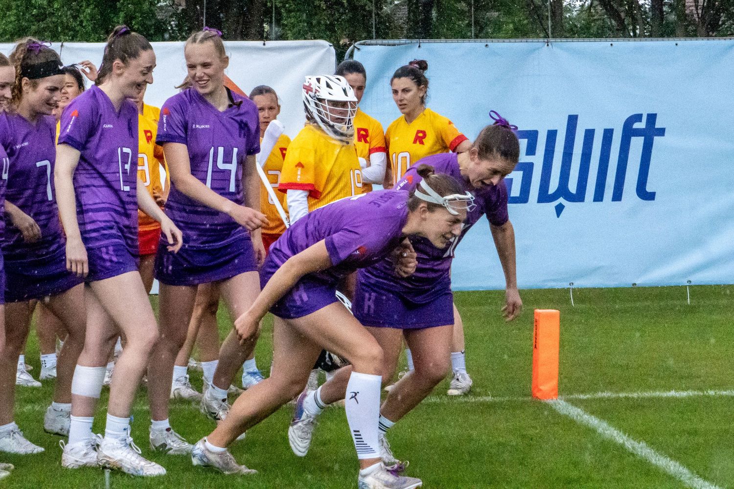 Purple-uniformed women's lacrosse team begins walk-on to pitch, with them bowing low just before running on.