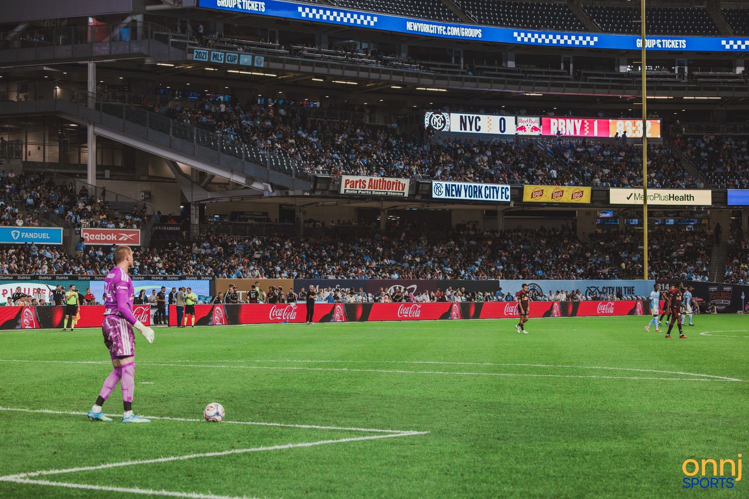 NYCFC goalkeeper prepares for a free kick during an MLS match at Yankee Stadium with fans in the stands.