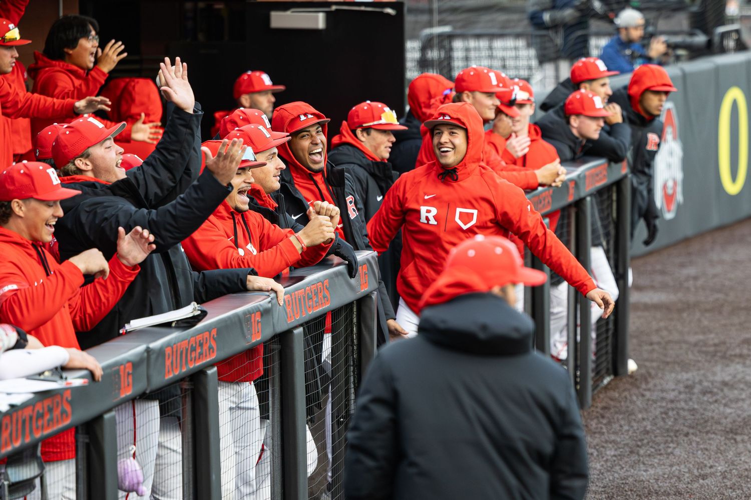 Ohio State Buckeyes baseball team celebrating in the dugout wearing red uniforms during a college baseball game.