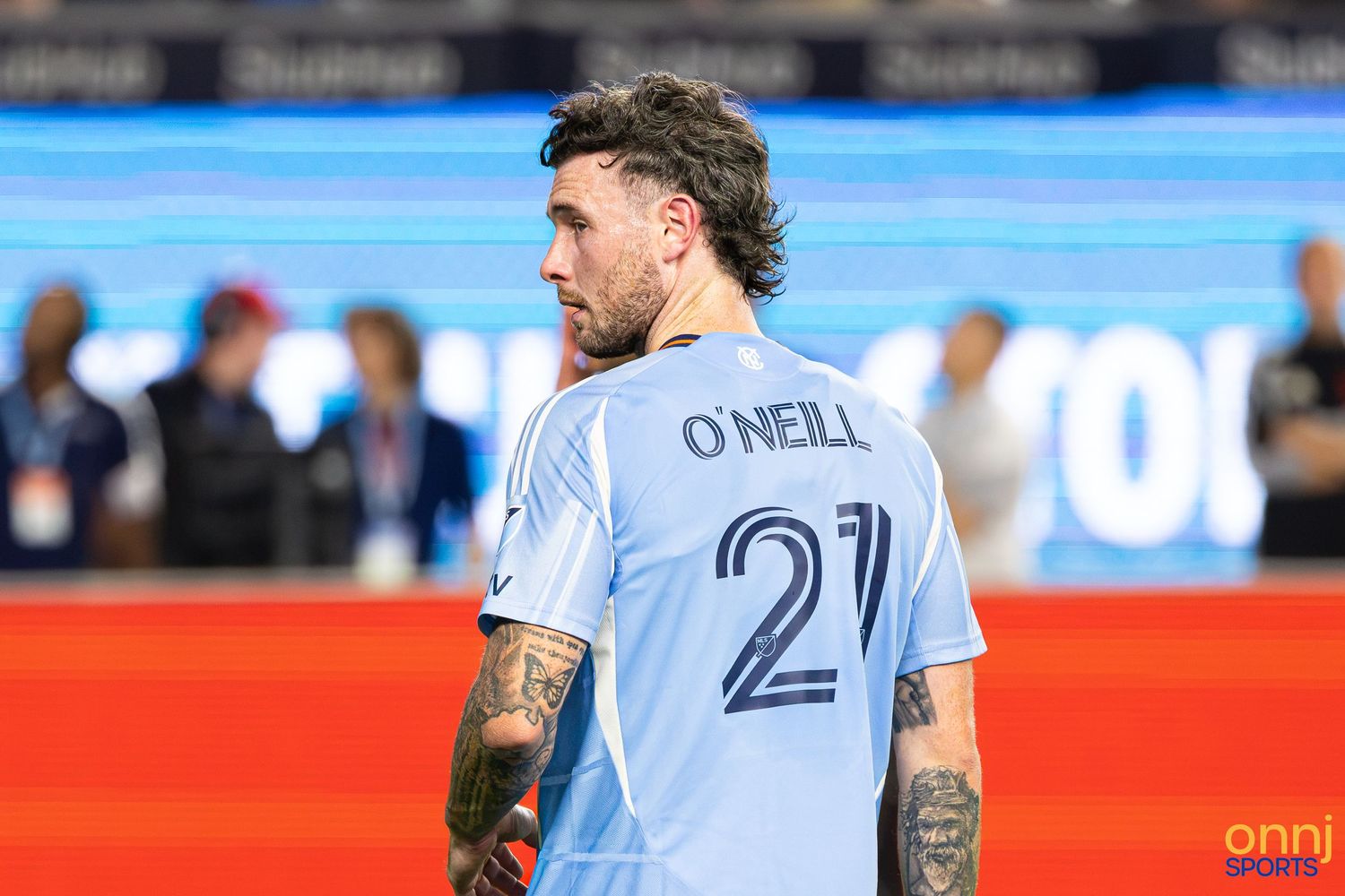 Soccer player O'Neill wearing number 21 light blue jersey with tattoos visible, standing on field during MLS match.