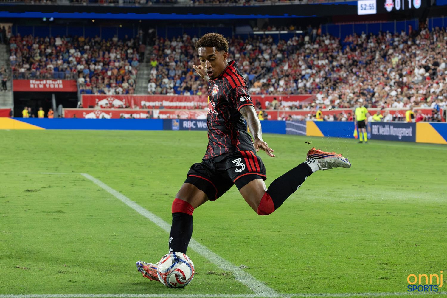 Soccer player wearing number 3 jersey performs a precise kick during an MLS match in a packed stadium.