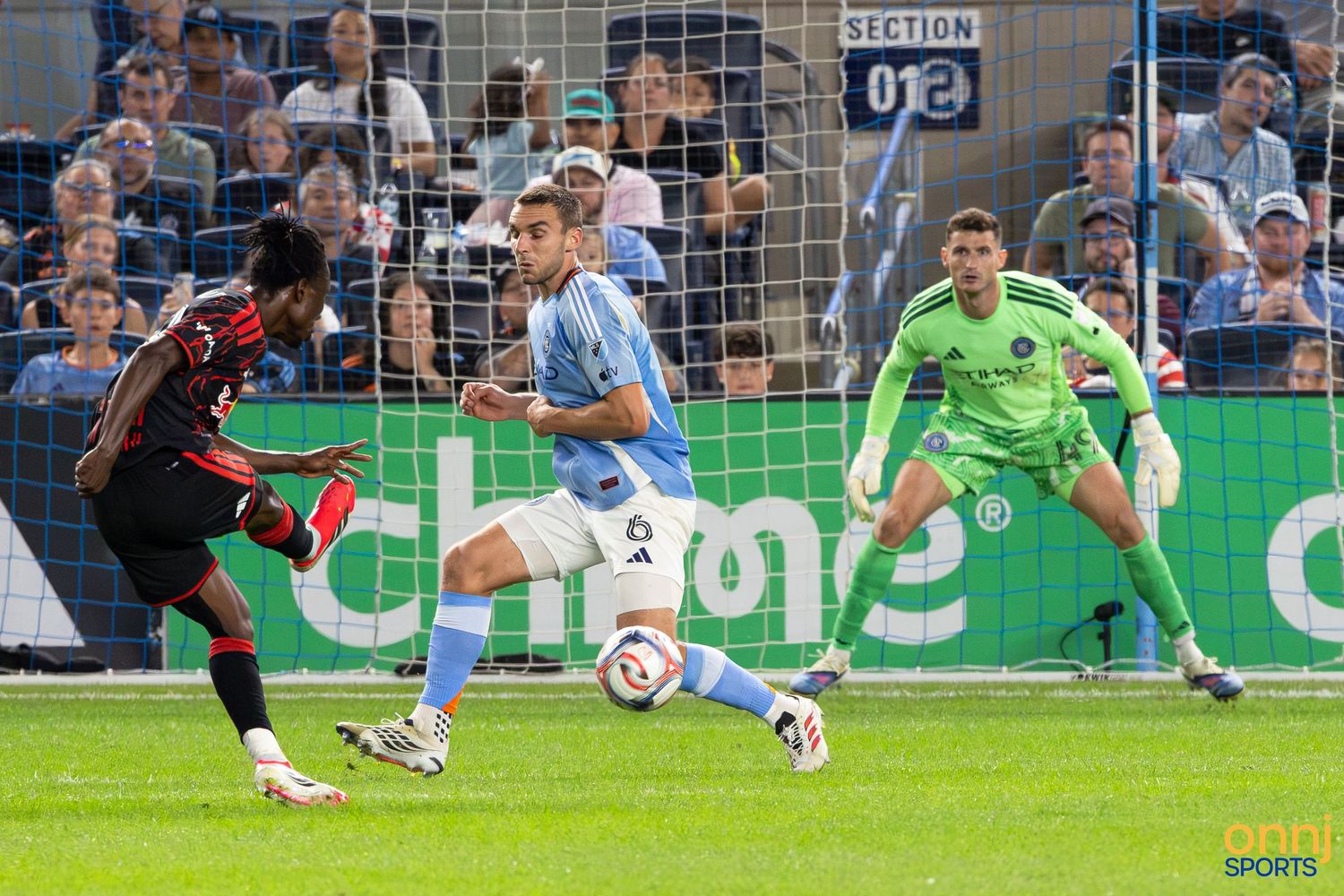 Soccer players compete for the ball during an MLS match, with a goalkeeper watching from the goal area.