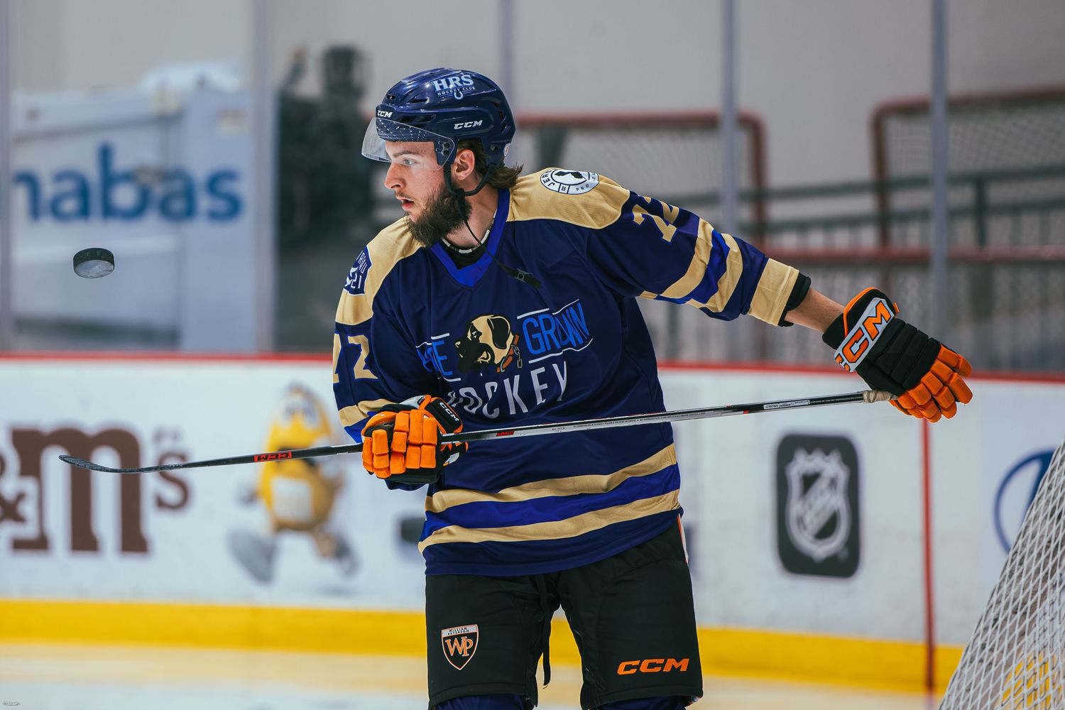Ice hockey player in navy blue uniform gesturing on the rink during a game.