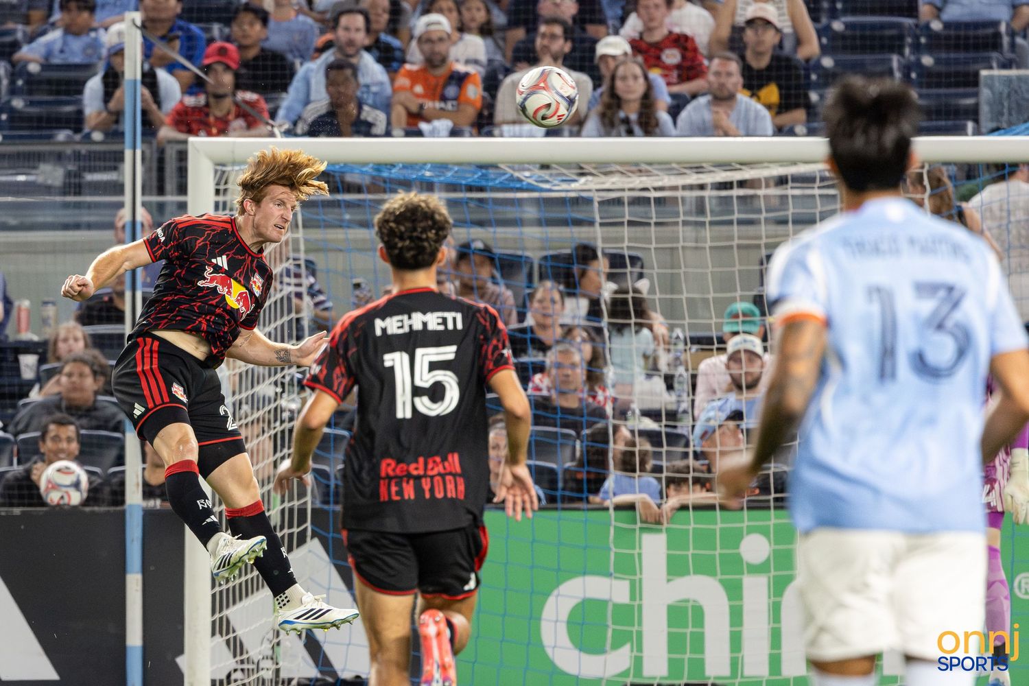 Soccer players compete for a header near the goal during an MLS match, with player #15 Mehmet visible.