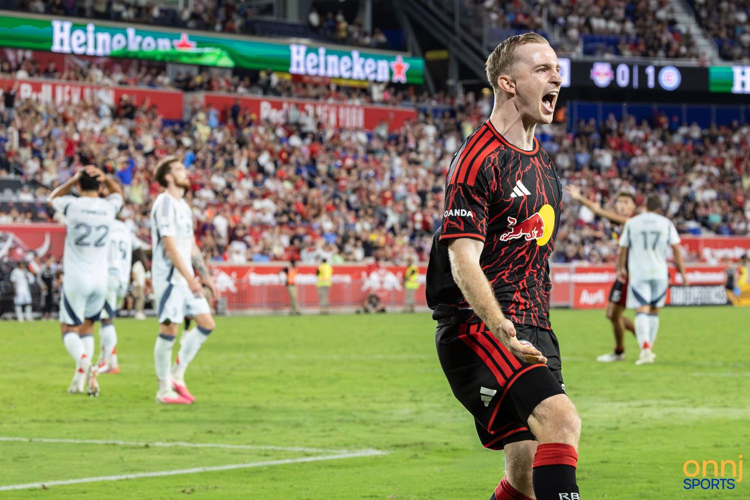 A New York Red Bulls soccer player celebrates a goal with an open-mouth roar at Red Bull Arena during an MLS match.