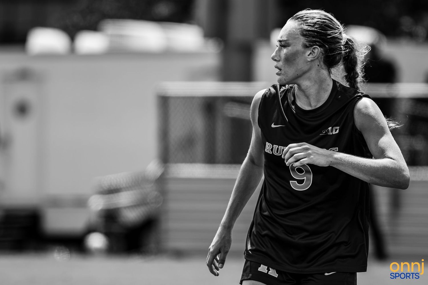 Black and white photo of a female athlete in jersey number 9 running on a sports field during a game.