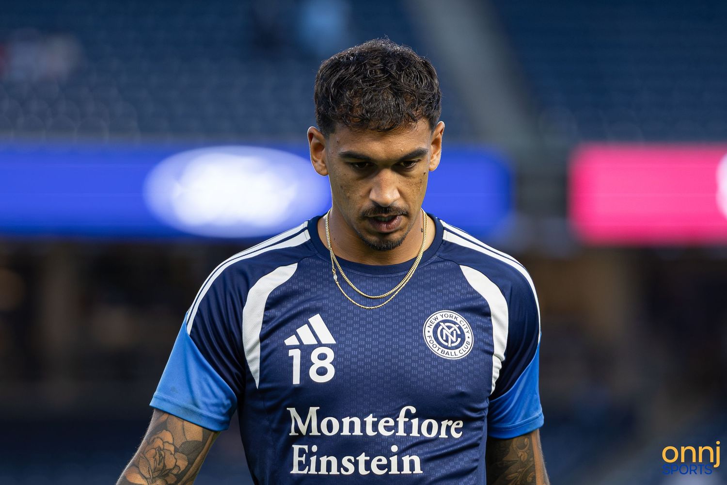 Soccer player wearing navy blue jersey number 18 with Montefiore Einstein sponsor on field.