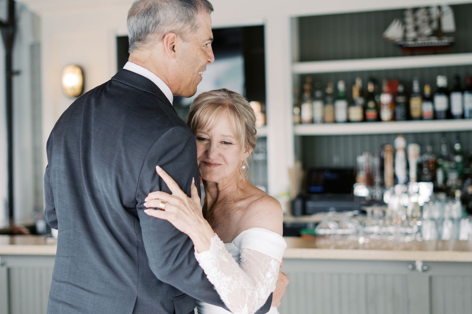 Detail-focused candid shot of a bride resting her head on the groom's shoulder during a reception dance at a Rhode Island wedding.