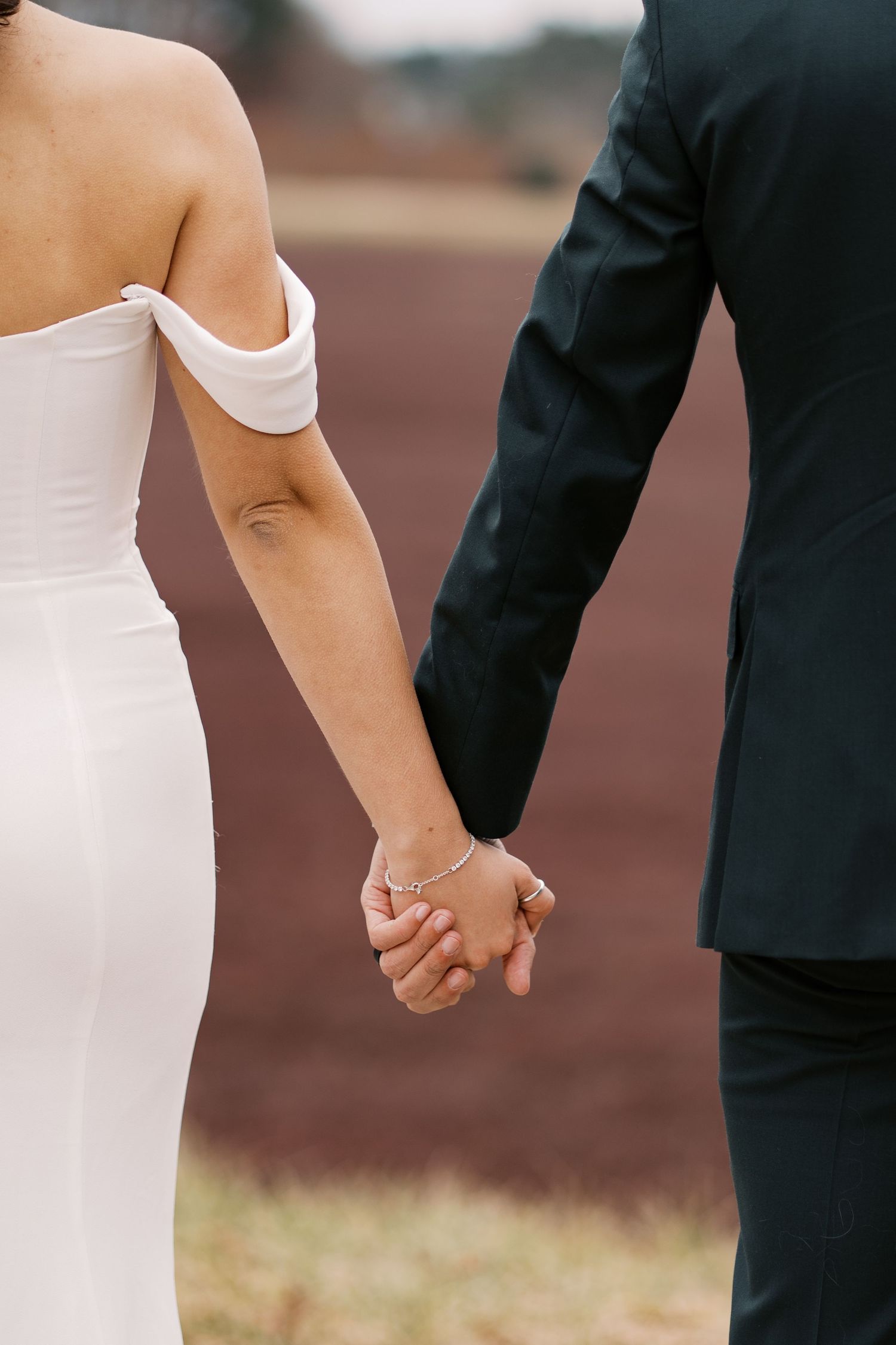 Candid shot of a bride and groom holding hands while walking through the frosted winter landscape at Rosebrook Event Center.