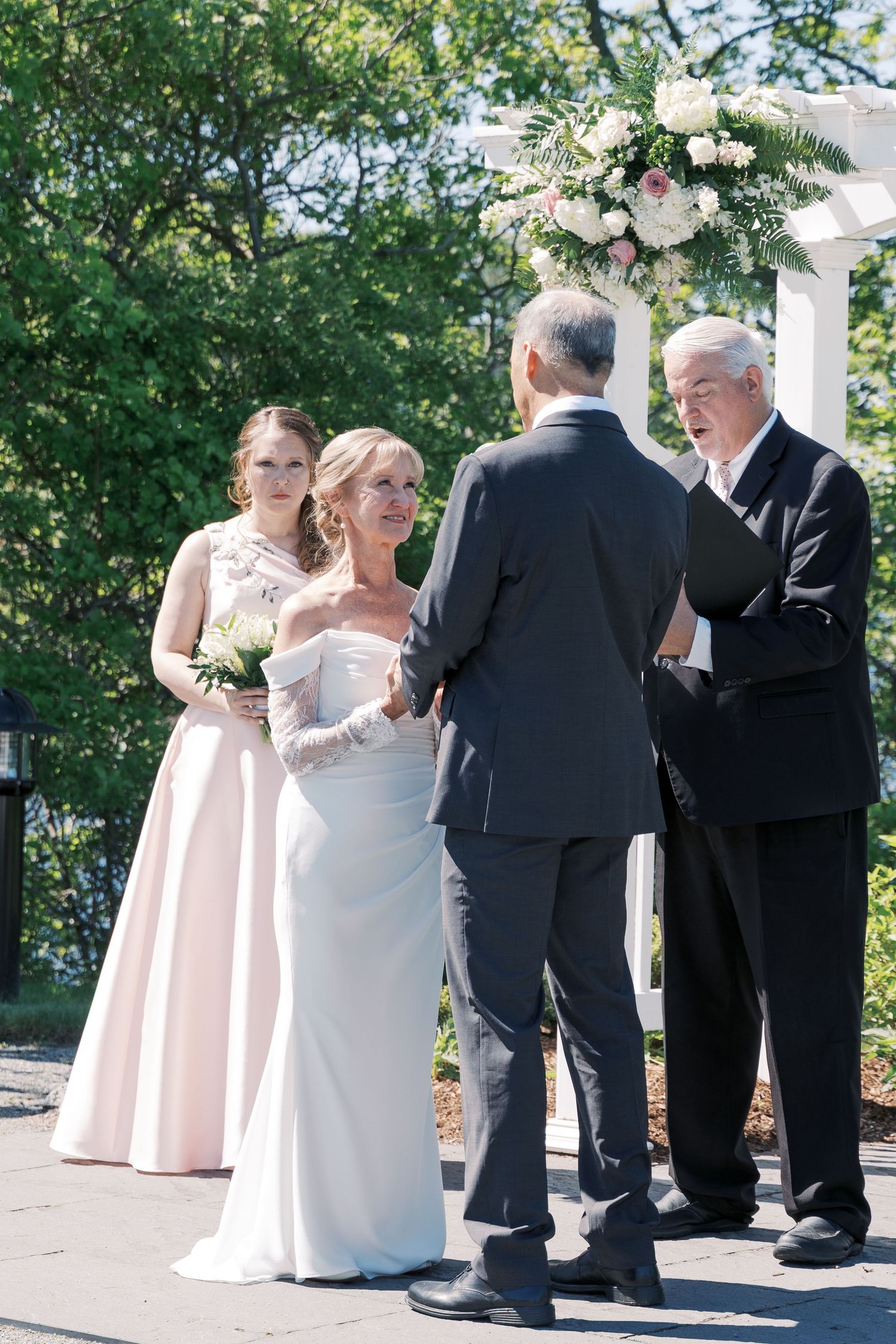 Candid moment of a bride and groom holding hands and exchanging vows at an outdoor coastal Rhode Island wedding.