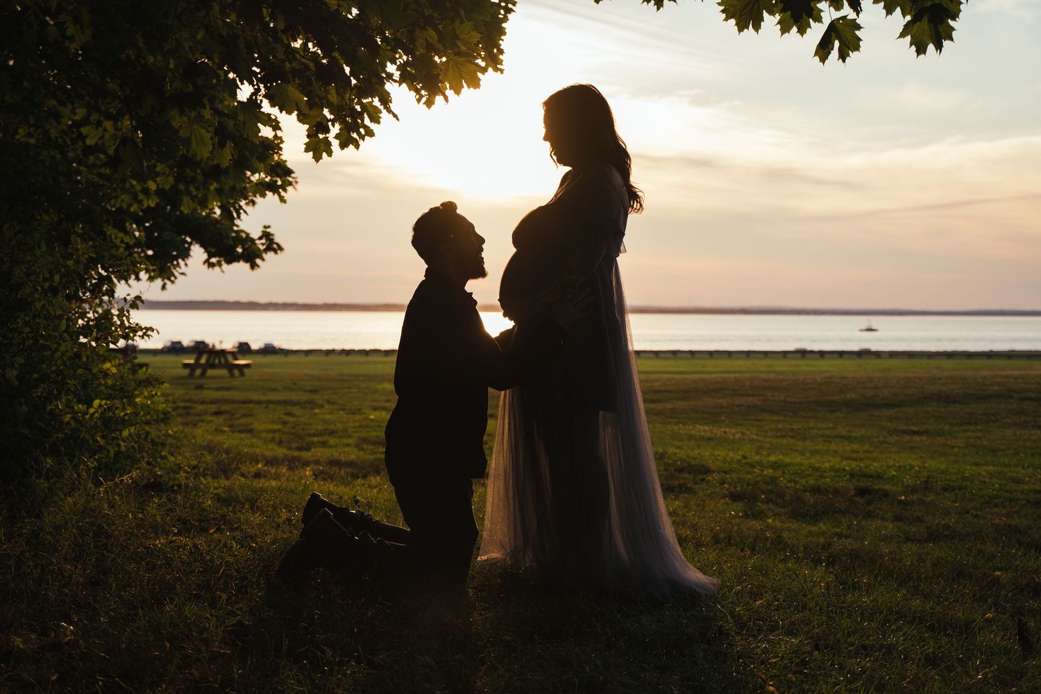 Silhouette photo of a man kissing his wife's belly at a Maternity shoot taken at Colt State Park in Bristol, RI.