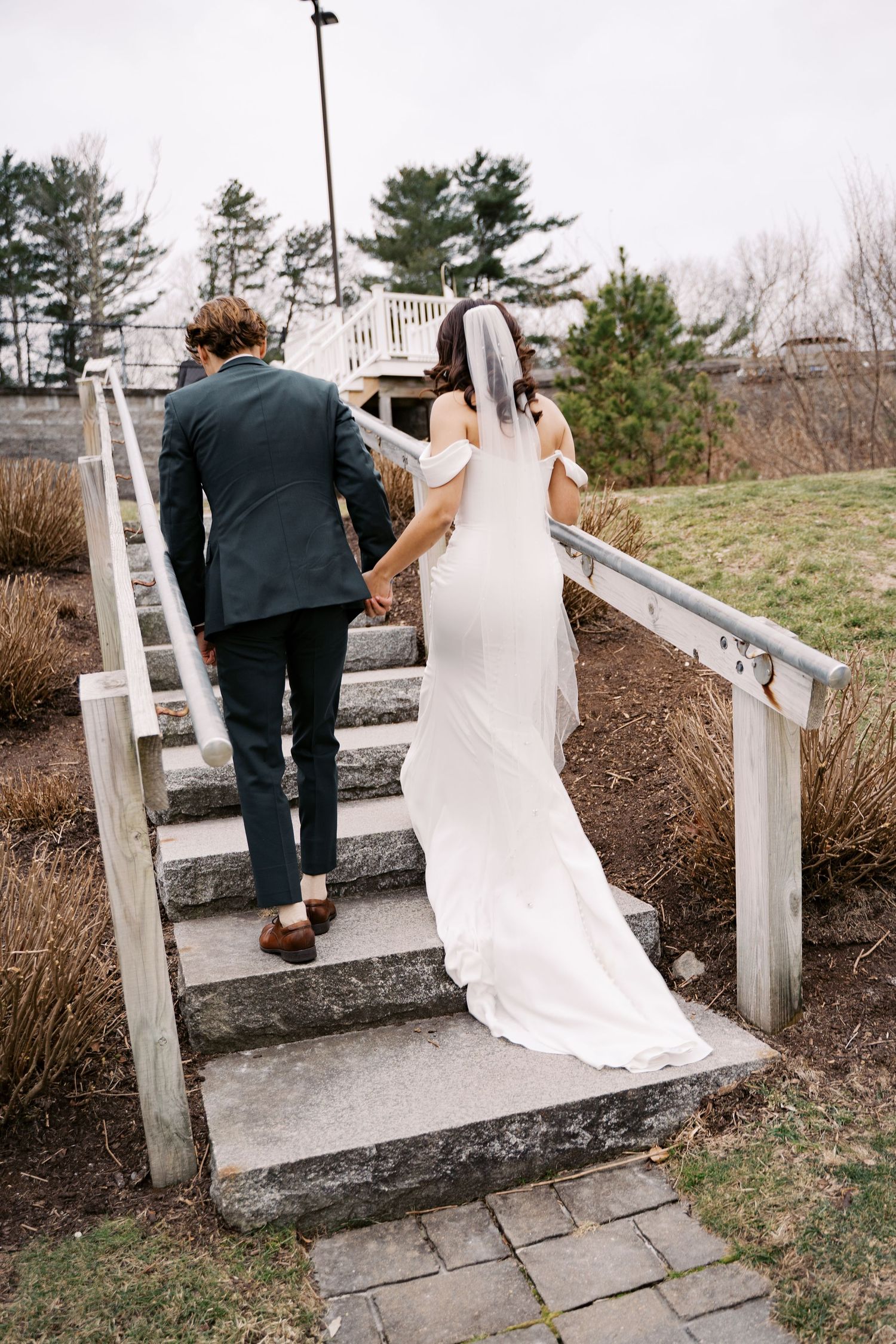 Newlyweds walking up the stairs together after their outdoor winter wedding ceremony at Rosebrook.