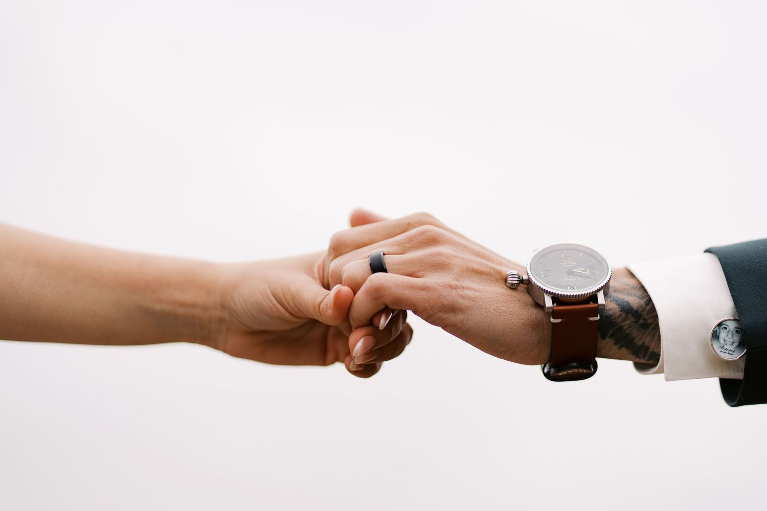 Two hands of newlyweds with a white backdrop of a cloudy sky in Wareham, MA.