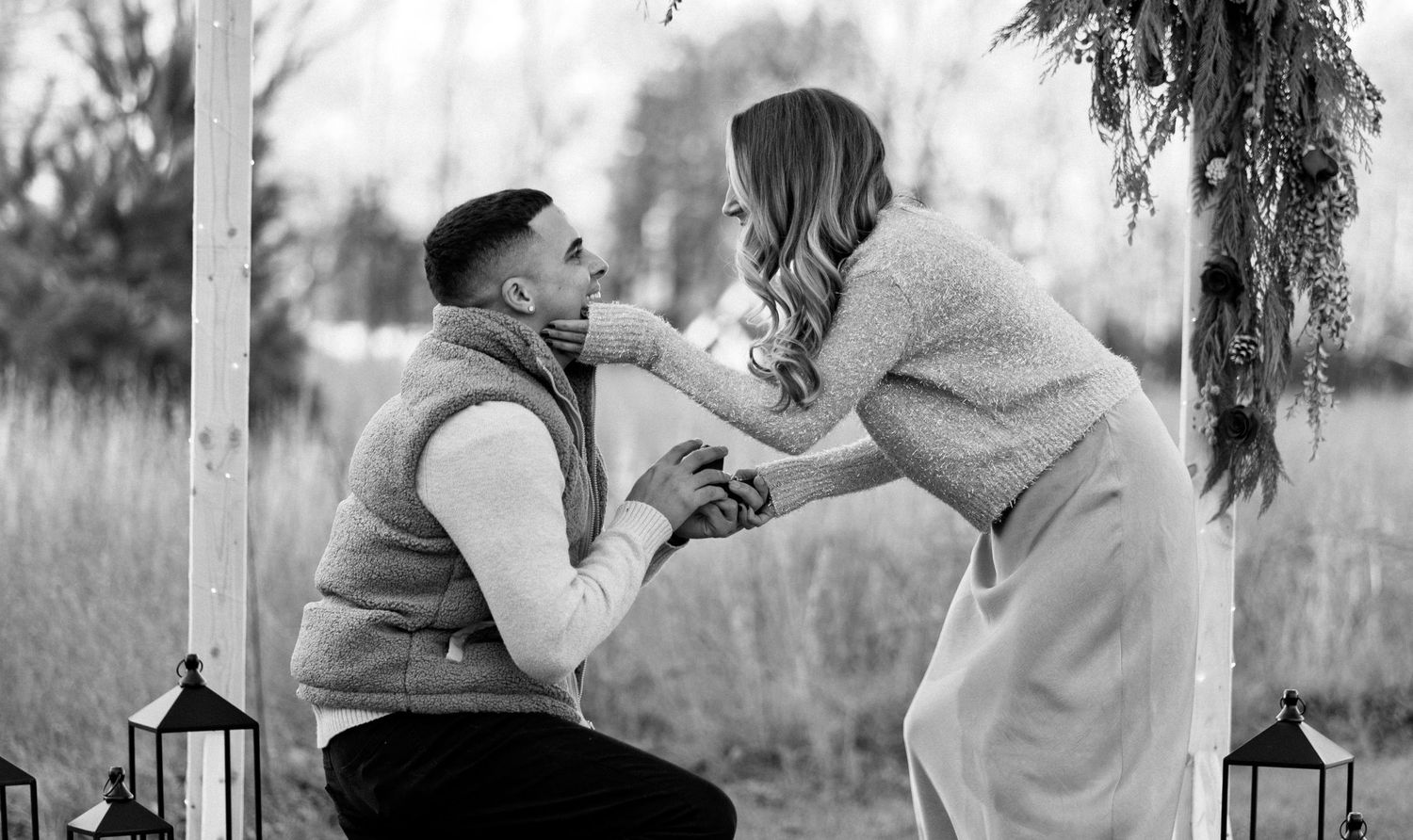 A black and white shot of a proposal with an arbor draped in winter florals in Boyden Park, Taunton MA.