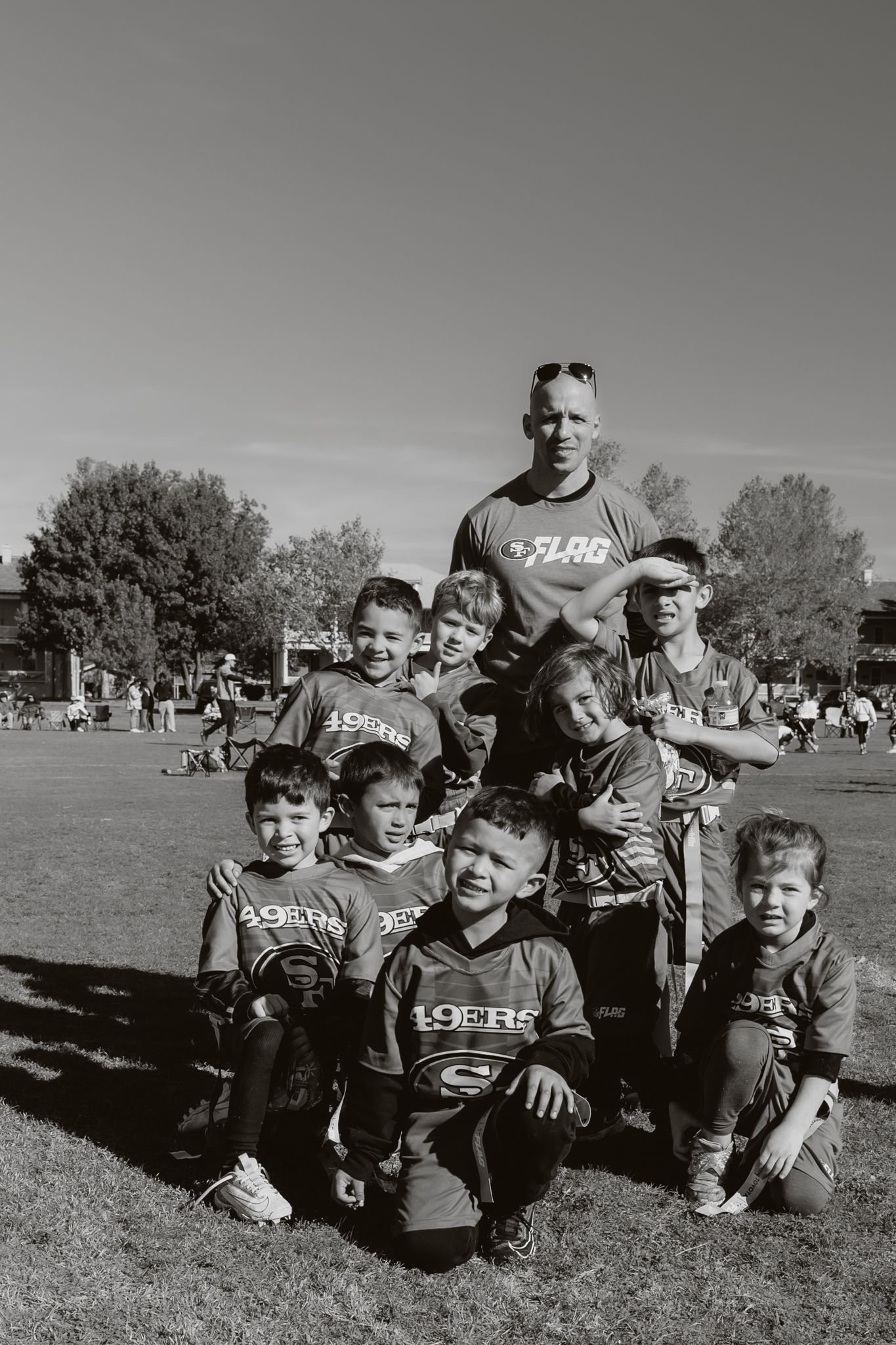 Vintage black and white panorama of youth football players and coaches on a grassy field.