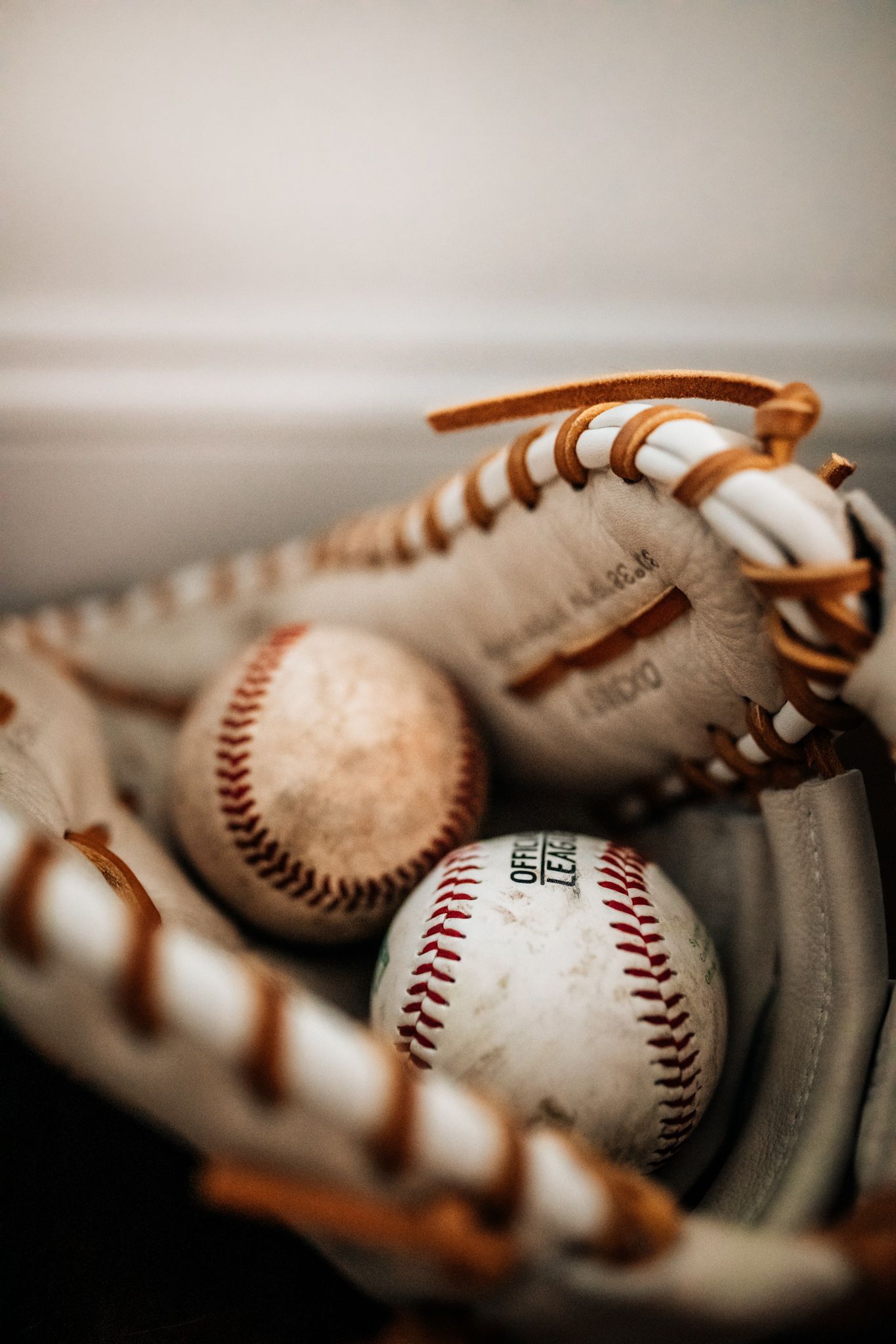 Close-up of baseball glove with baseballs in dramatic lighting.