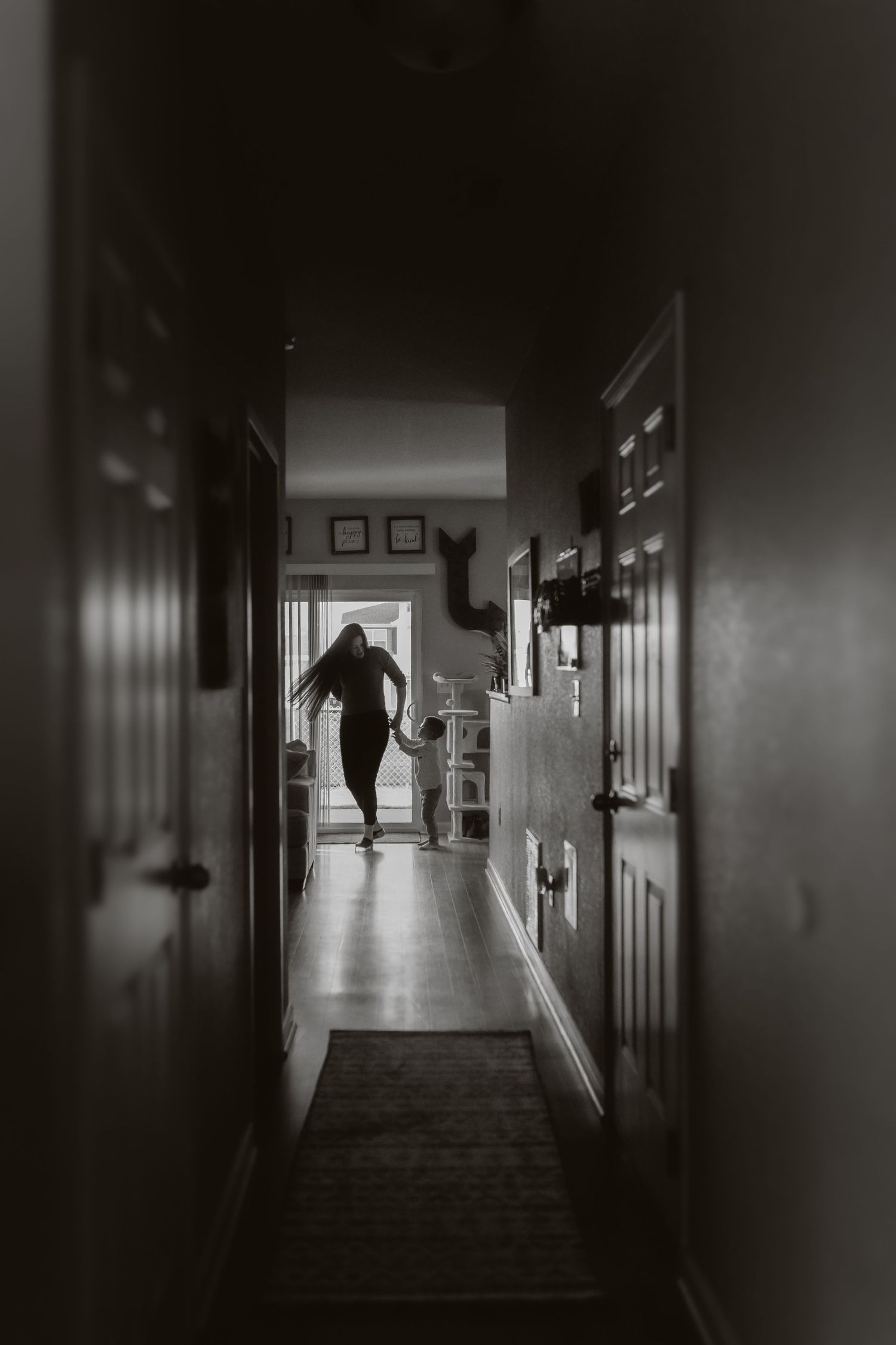 Silhouette of a person walking down a dark hallway in a dramatic black and white photograph.