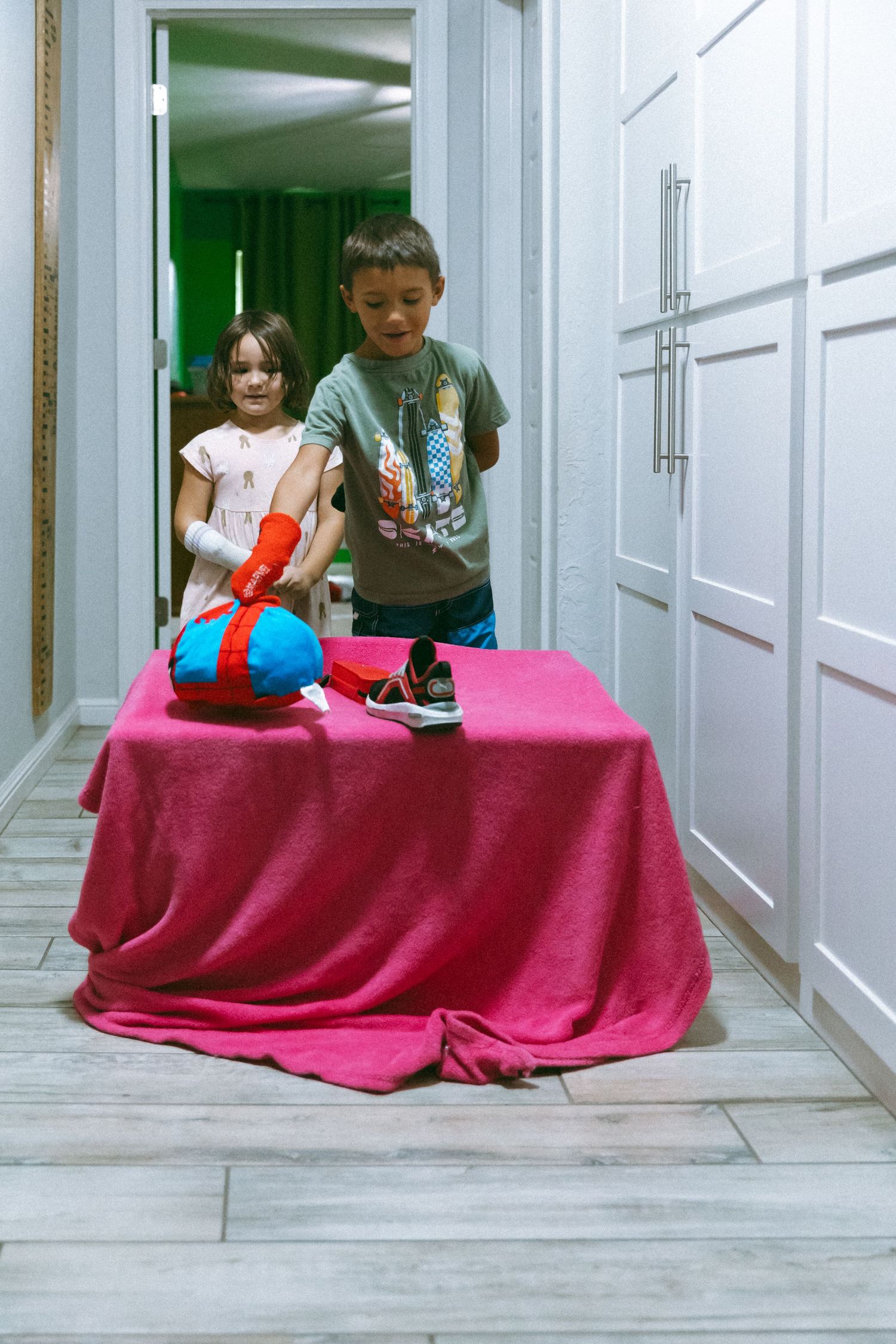A series of four photos showing people huddled under a pink blanket in a hallway.