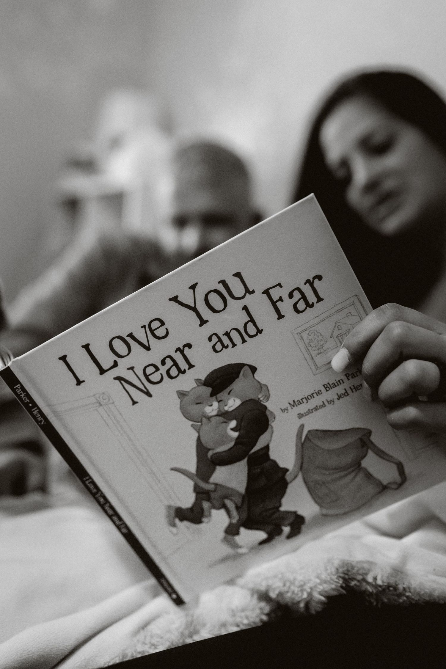 Reading a children's book titled 'I Love You Near and Far' in bed.