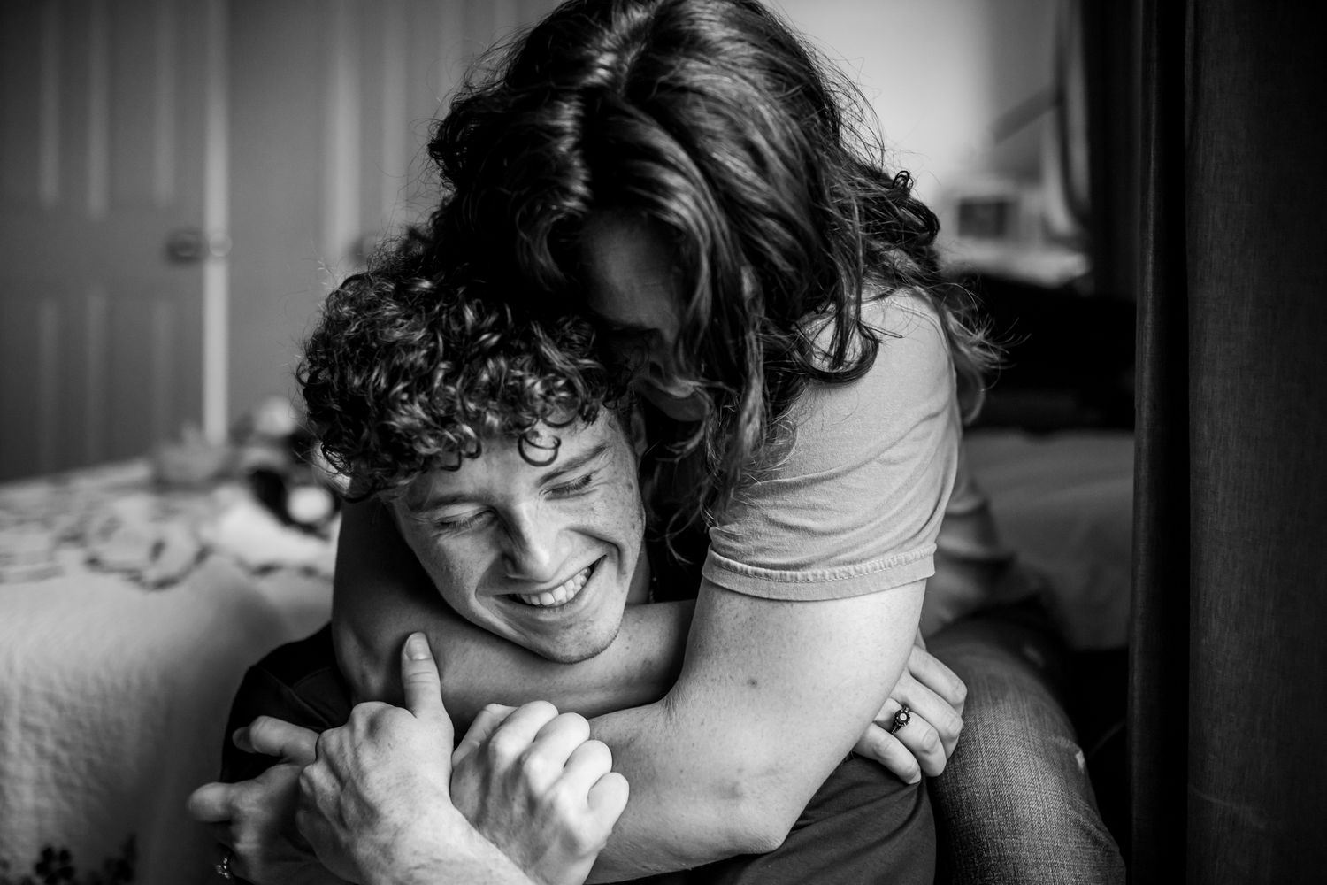Intimate black and white photo showing an affectionate embrace and shared laughter. In-Home Photography Liz Perez