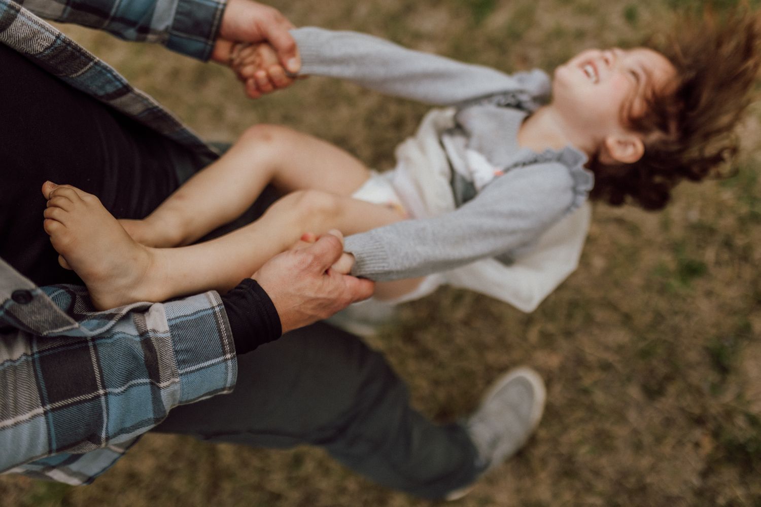Close-up view of daddy's hands twirling his daughter while she's still small enough to spin her.