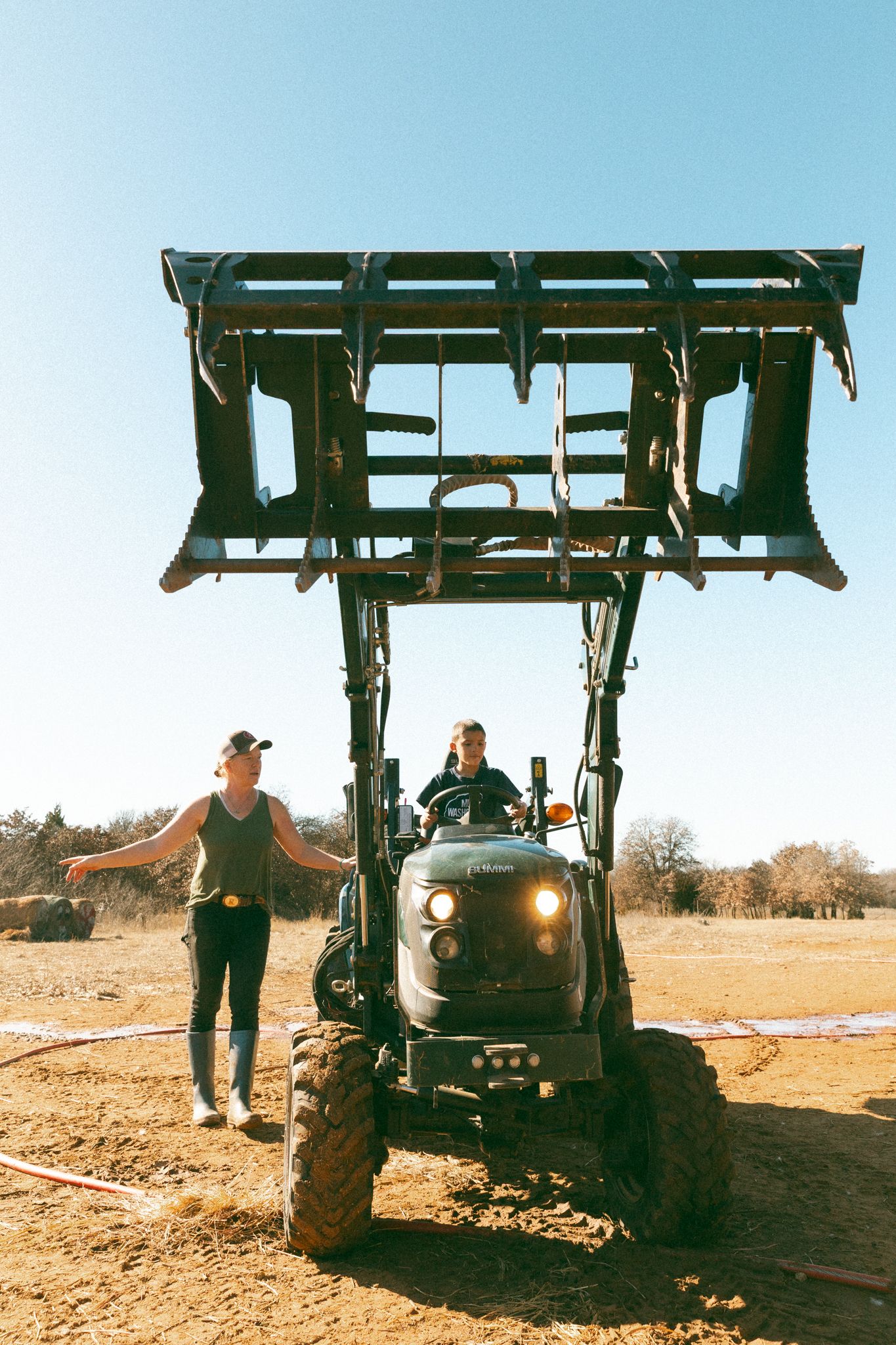Farm machinery working in a dusty field during agricultural operations.