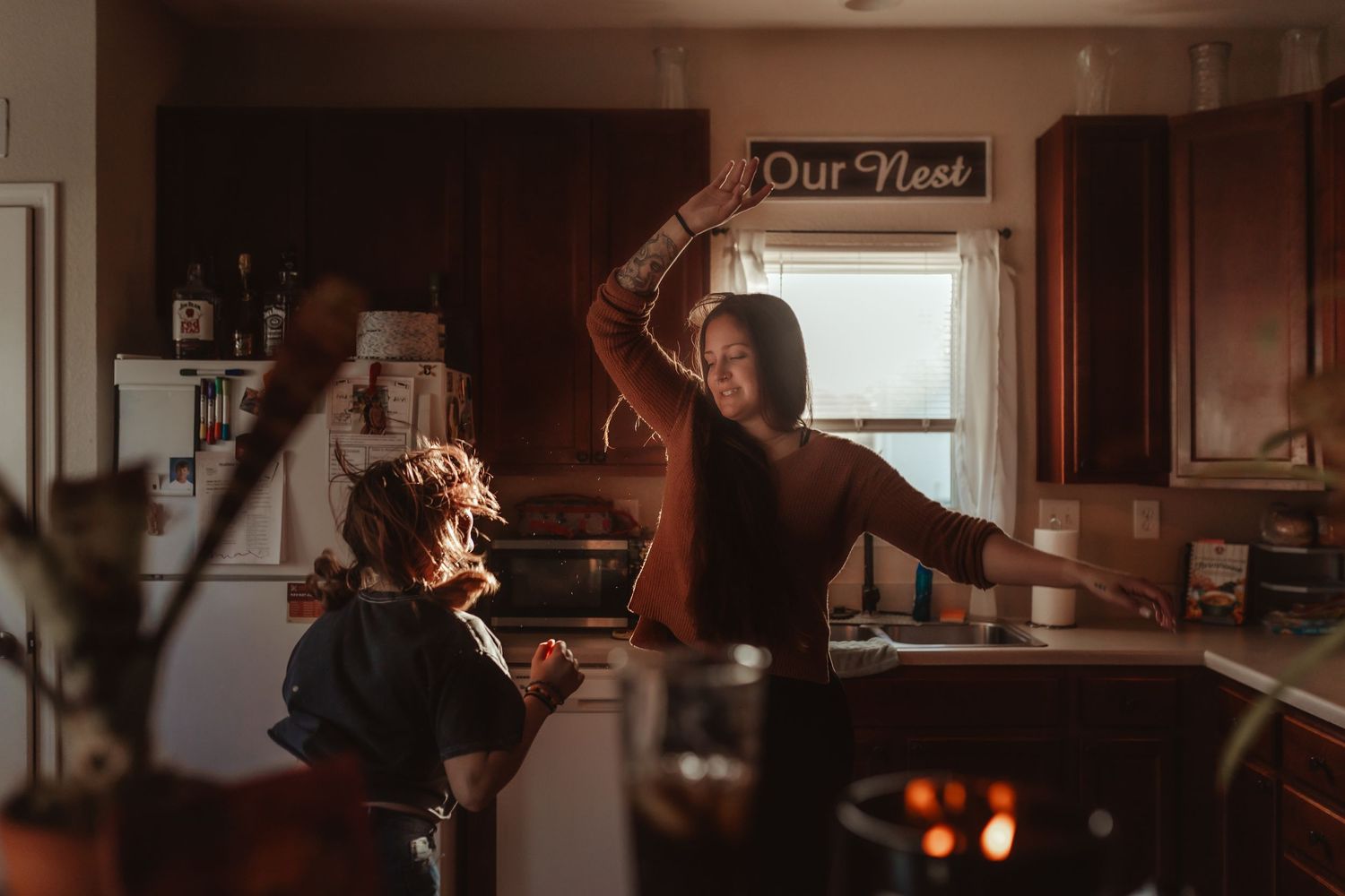 A tender moment shared between two people dancing in a sunlit kitchen.