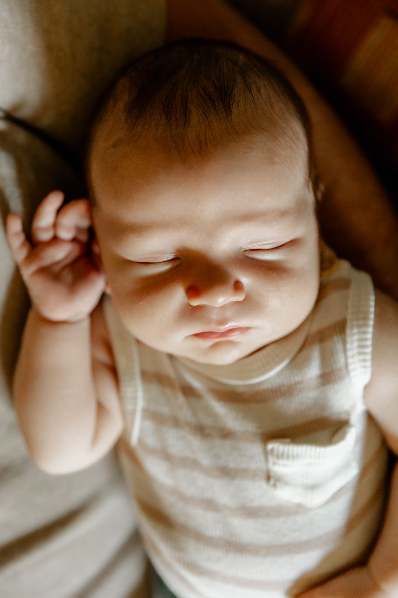 Peaceful sleeping newborn baby in soft white clothing photographed from different closeup angles.