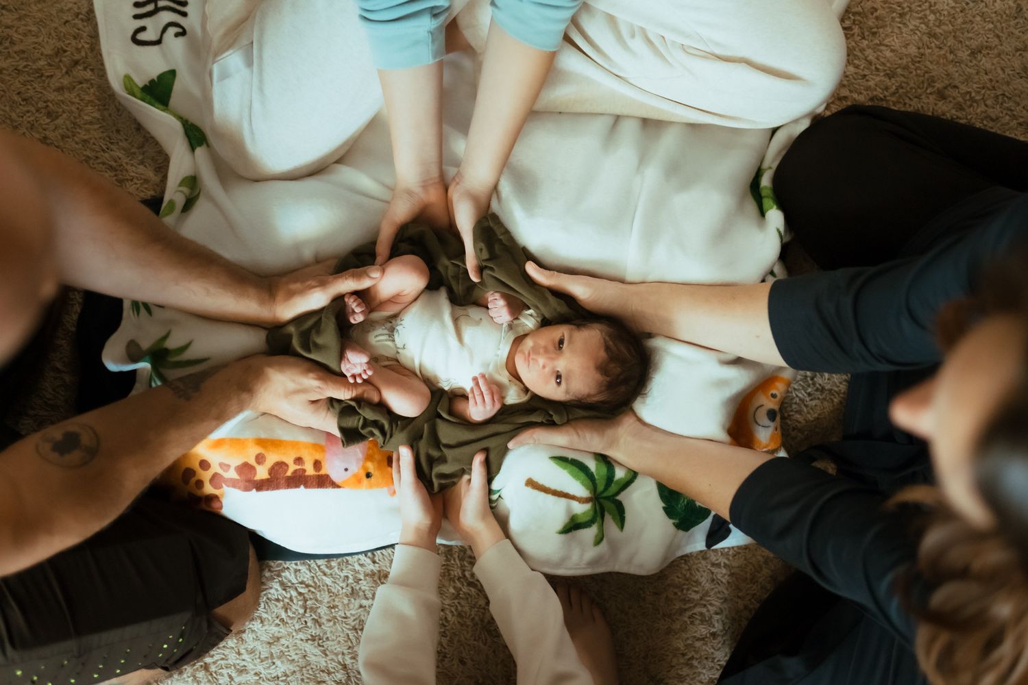 Overhead view of people sharing pizza and snacks while relaxing on a carpet.