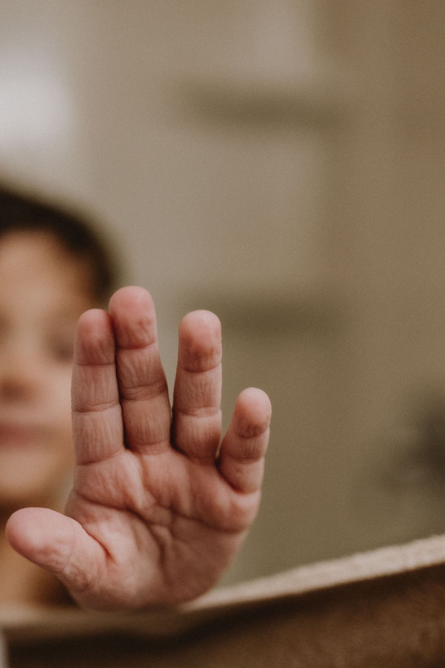Close-up shot of a small hand resting against a brown background.