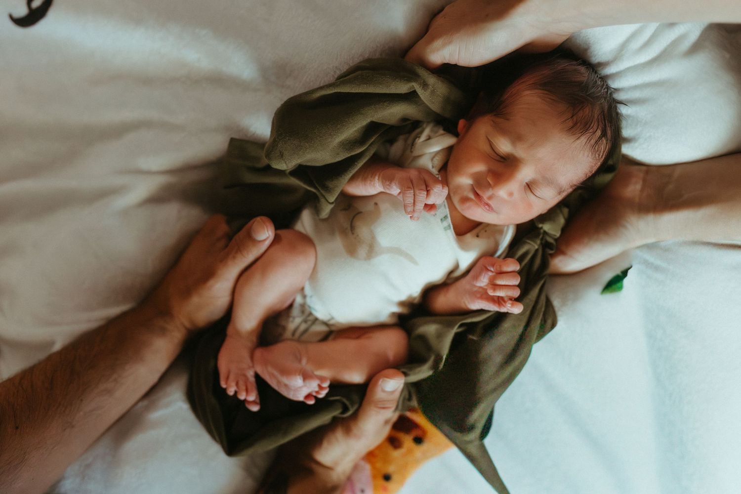 Tender moment captured on white bedding with natural window light.