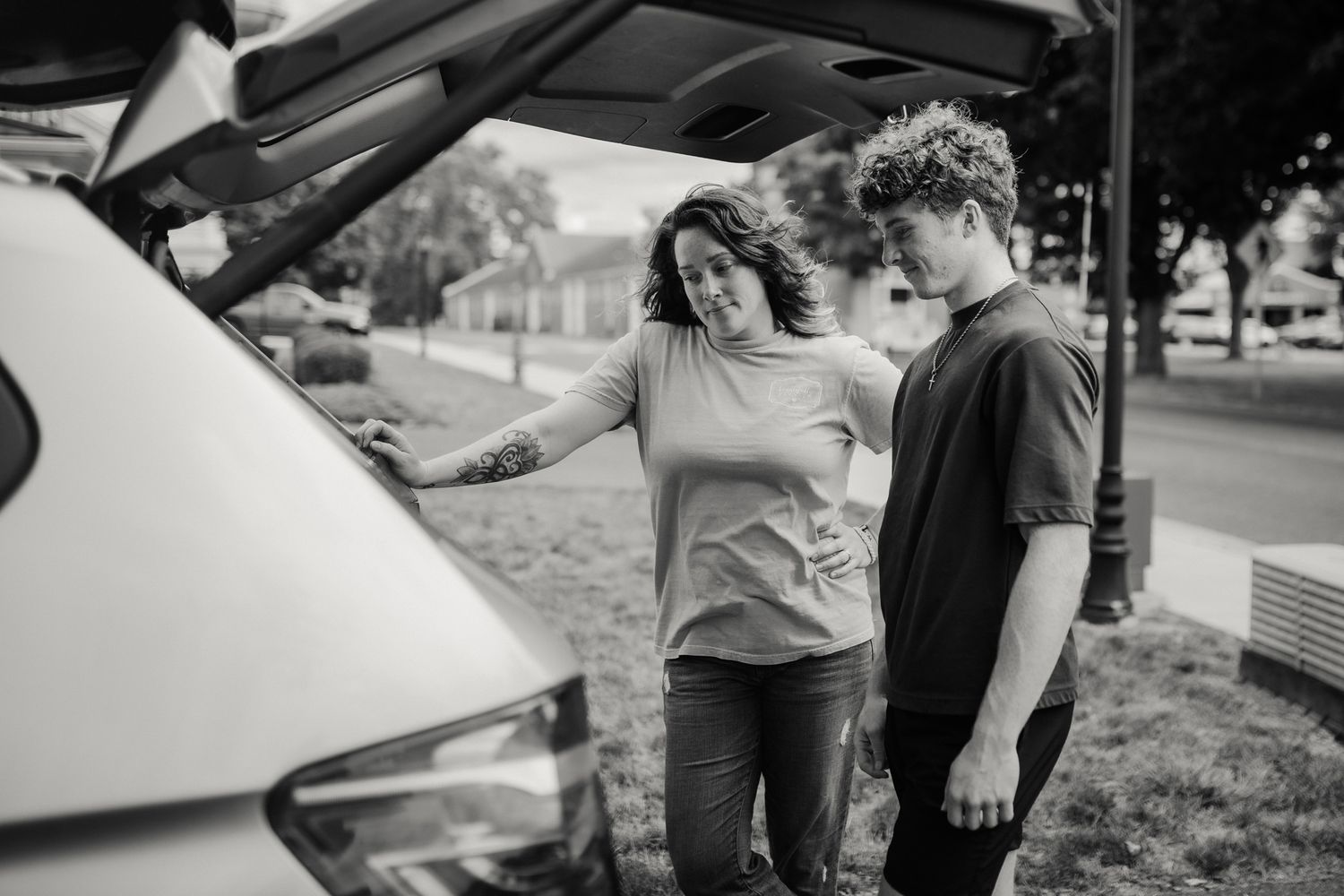 People gathered around examining a vehicle in a residential driveway.