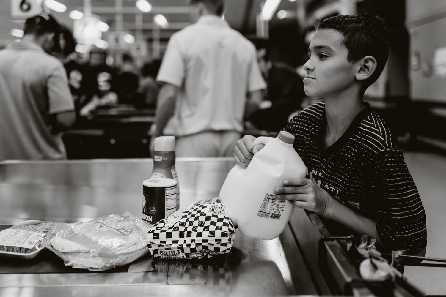 Group of people sitting at tables in a black and white photograph capturing a casual dining scene.