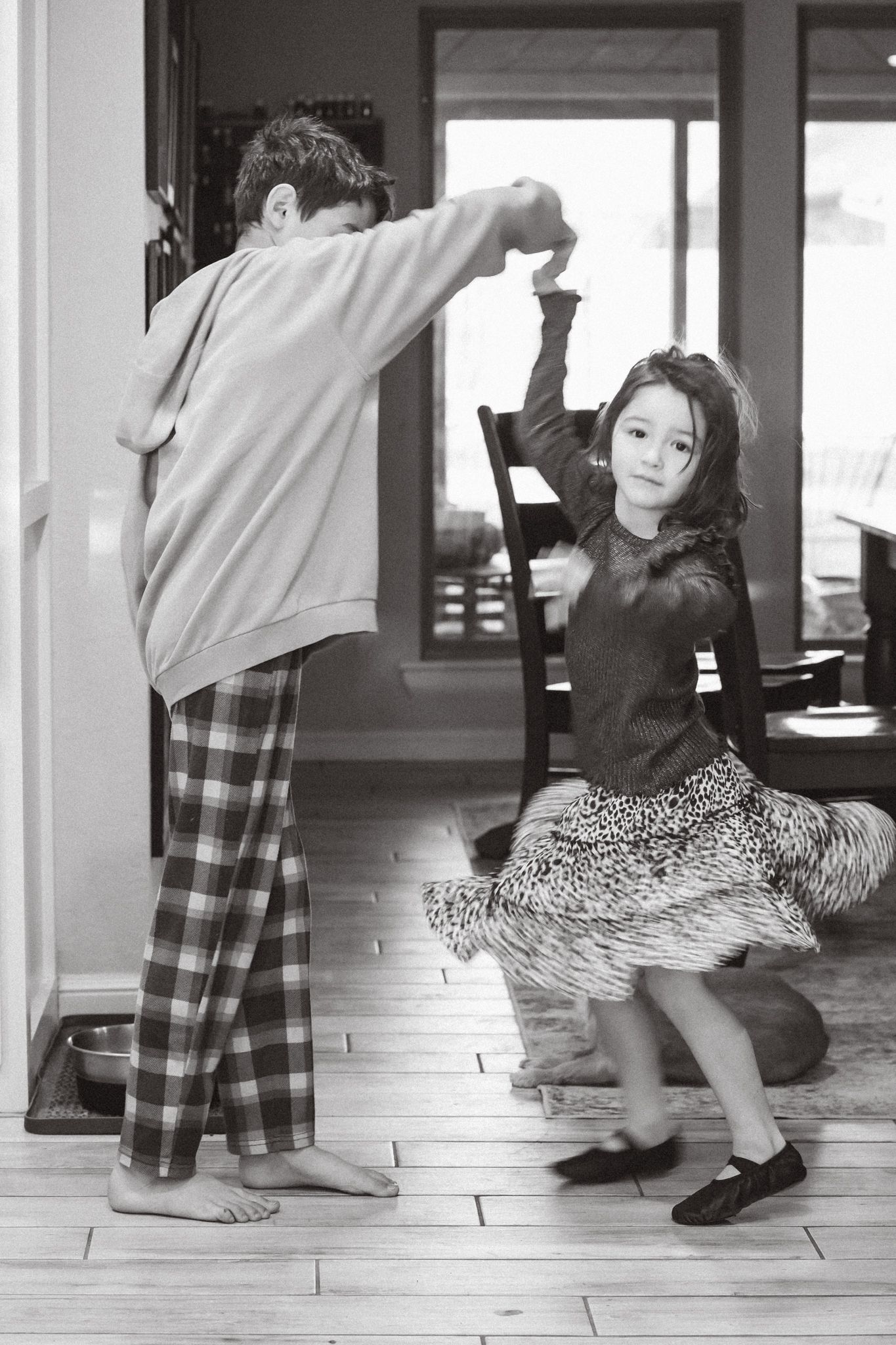 Series of black and white photos showing playful movement and dance poses on a hardwood floor.
