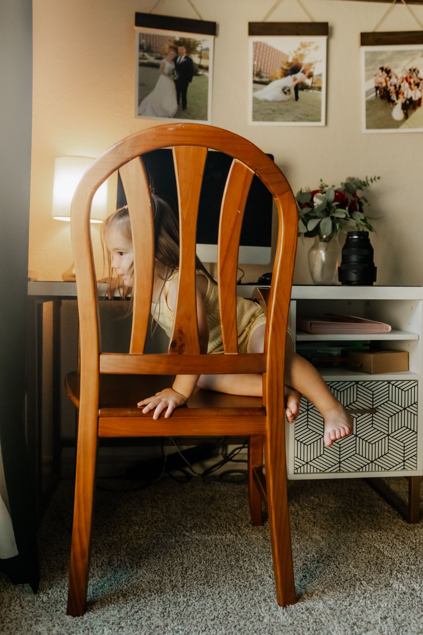 A progression of four images showing someone in casual clothing playfully crawling under a wooden dining chair.