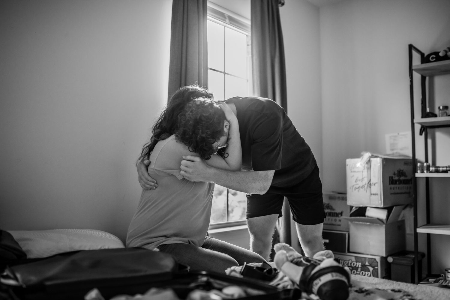 Black and white photo of two people studying together at a desk by window light.