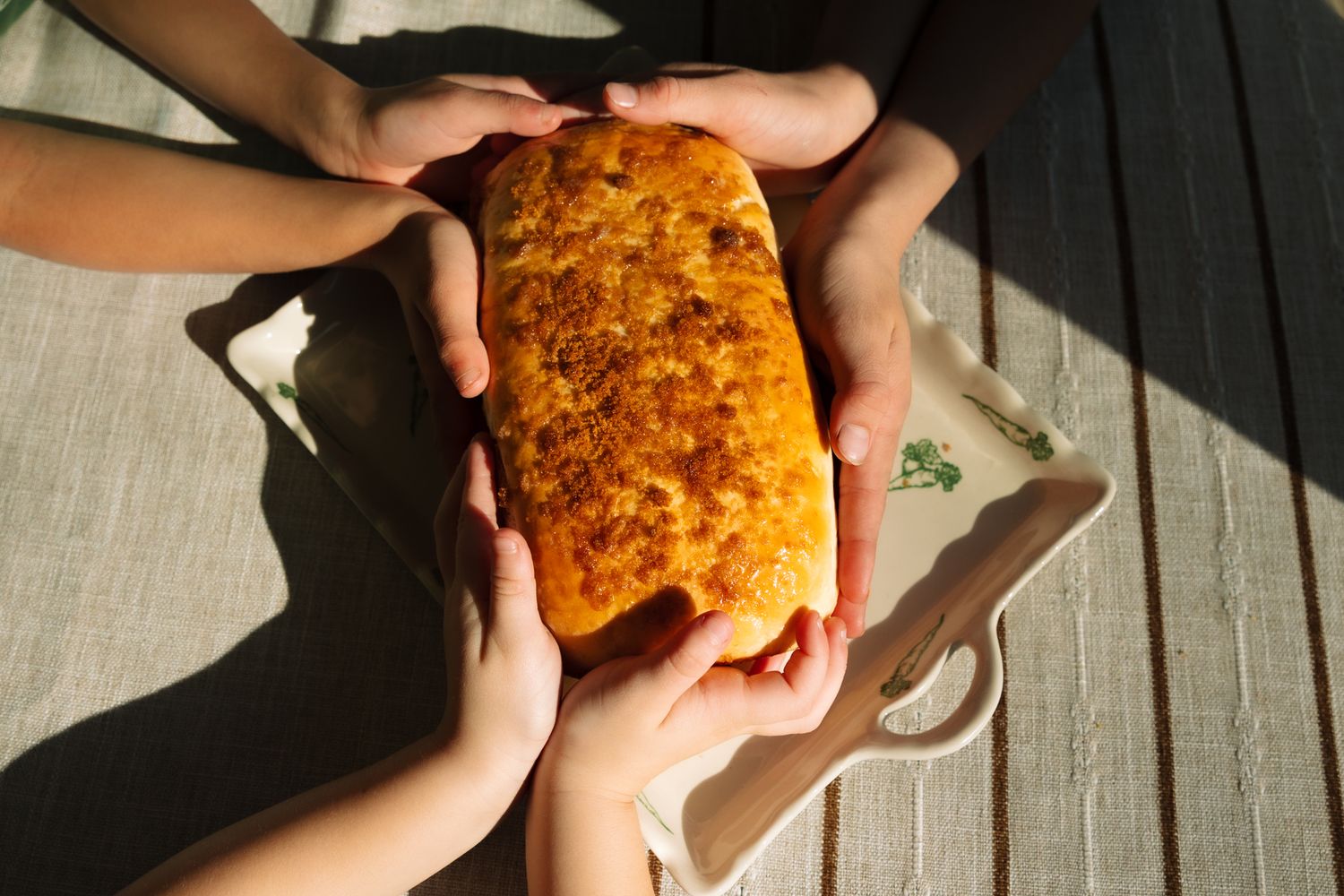 Close-up sequence of hands holding and examining a golden-brown baked item in sunlight.