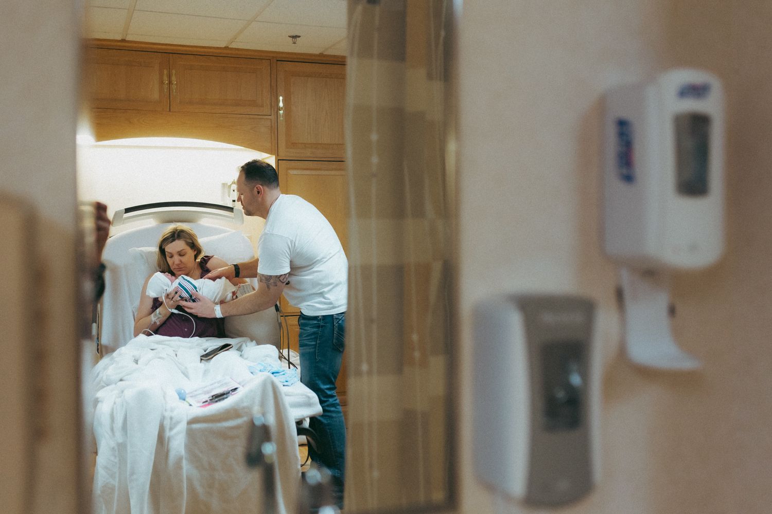 A patient rests in a hospital bed while being attended to by a medical professional in a clinical setting.