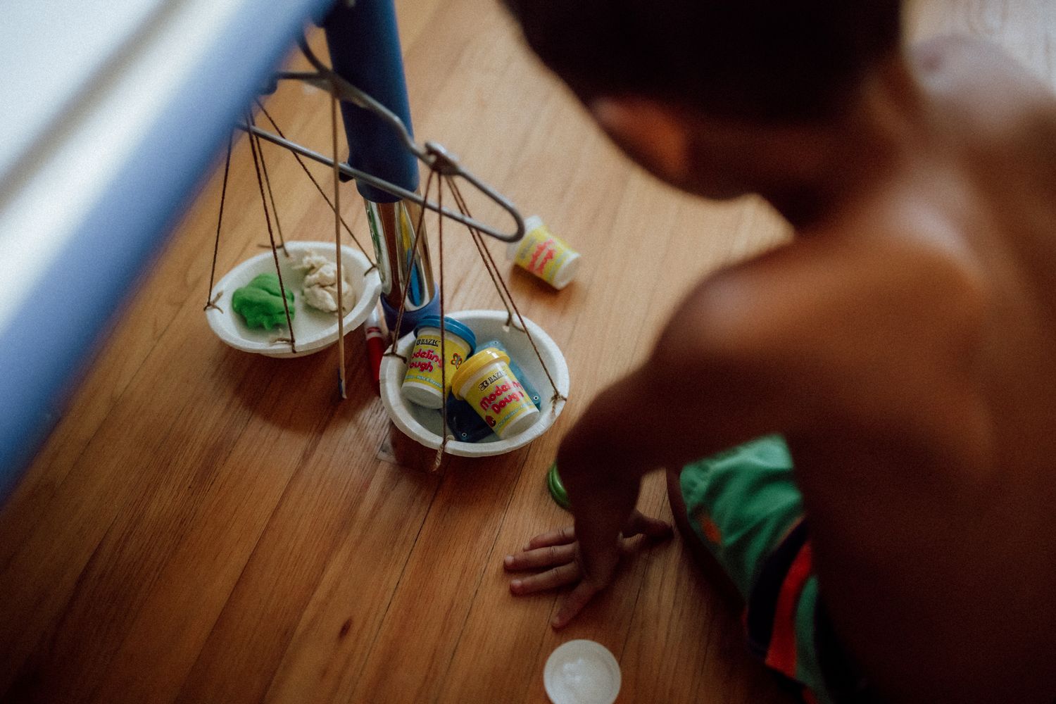 Balance scale with green objects being observed on wooden floor in dramatic lighting.