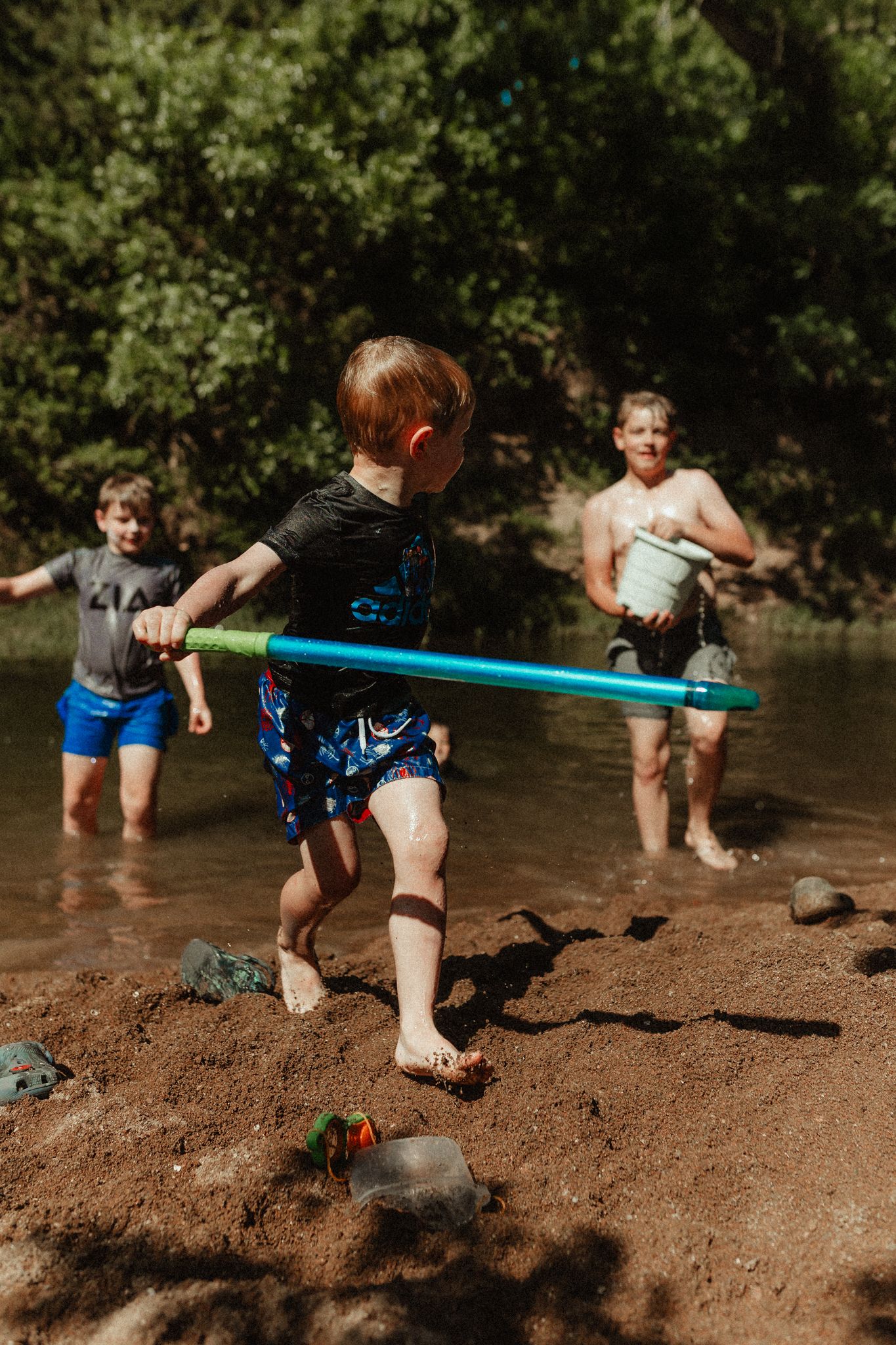 Children playing in shallow water at natural swimming area during summer fun.