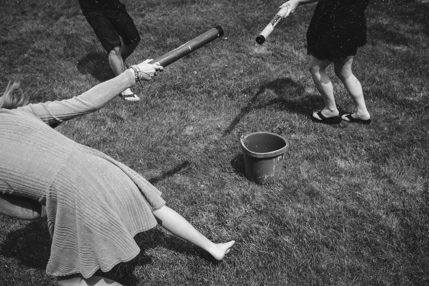 Black and white image of people with water guns playing on the lawn.