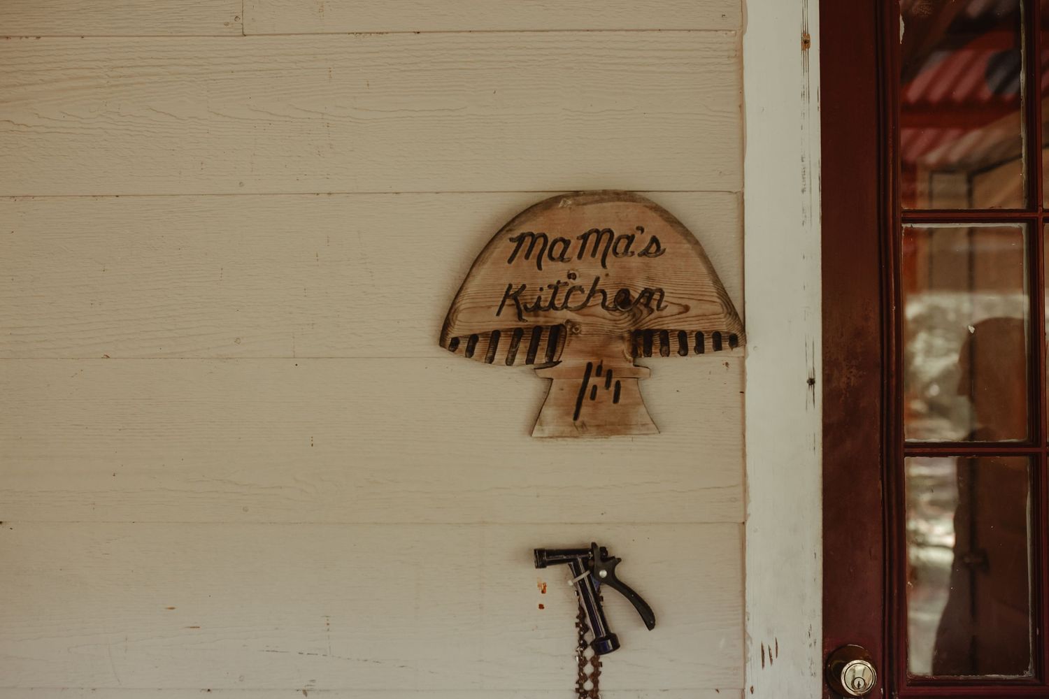 Rustic wooden porch exterior with vintage signs mounted on white siding.