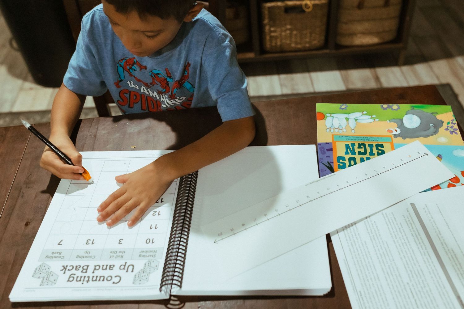 Student working on math or homework problems at a desk with textbooks and notebooks spread out. In-Home Photography Liz Perez