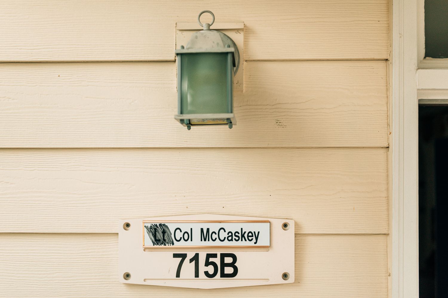 House number 715B on beige siding with green lantern fixture.
